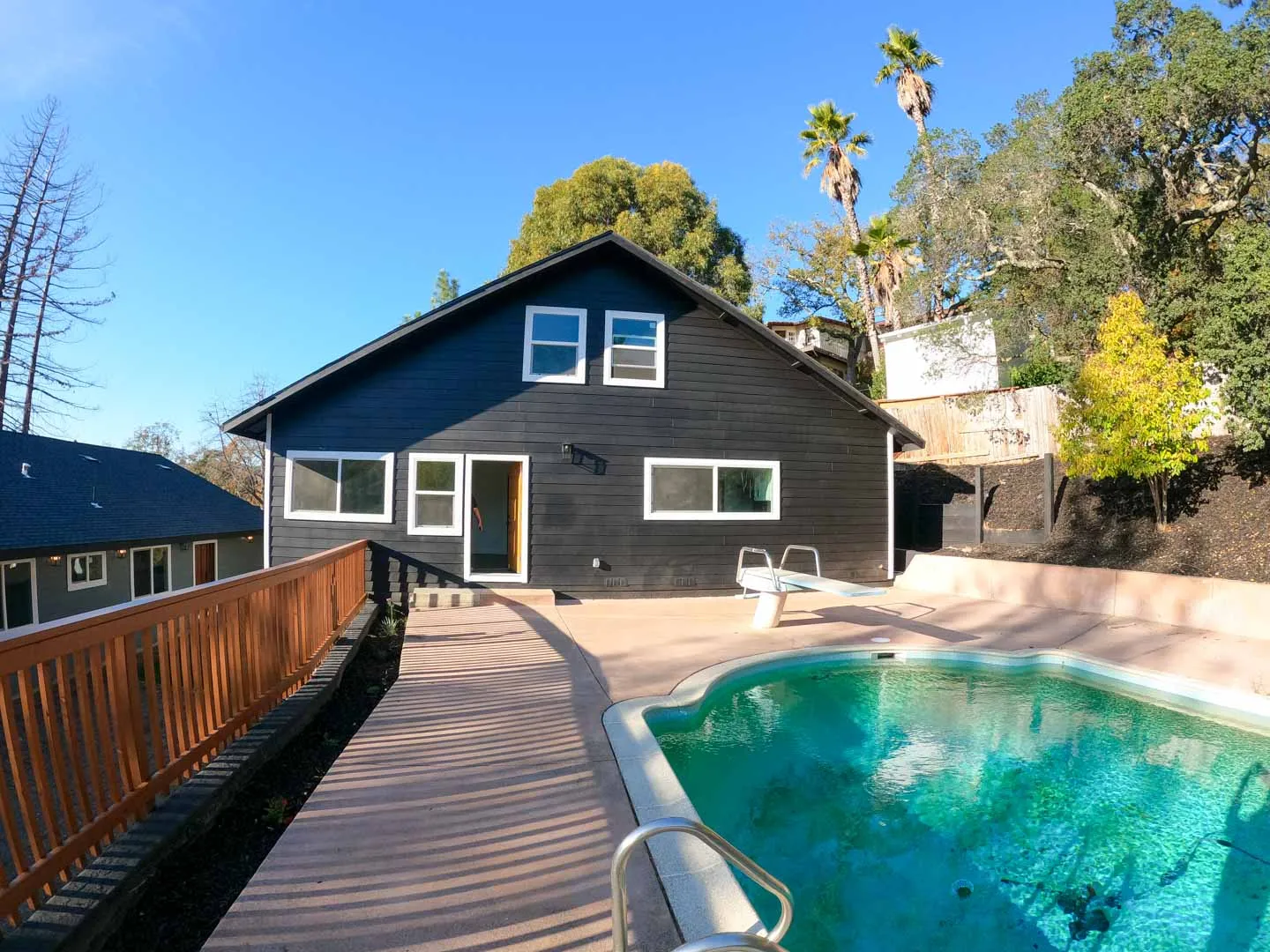 Modern full house new construction in Novato, CA featuring a sleek black exterior, large windows, and a private backyard pool built by Green Bay Remodeling.