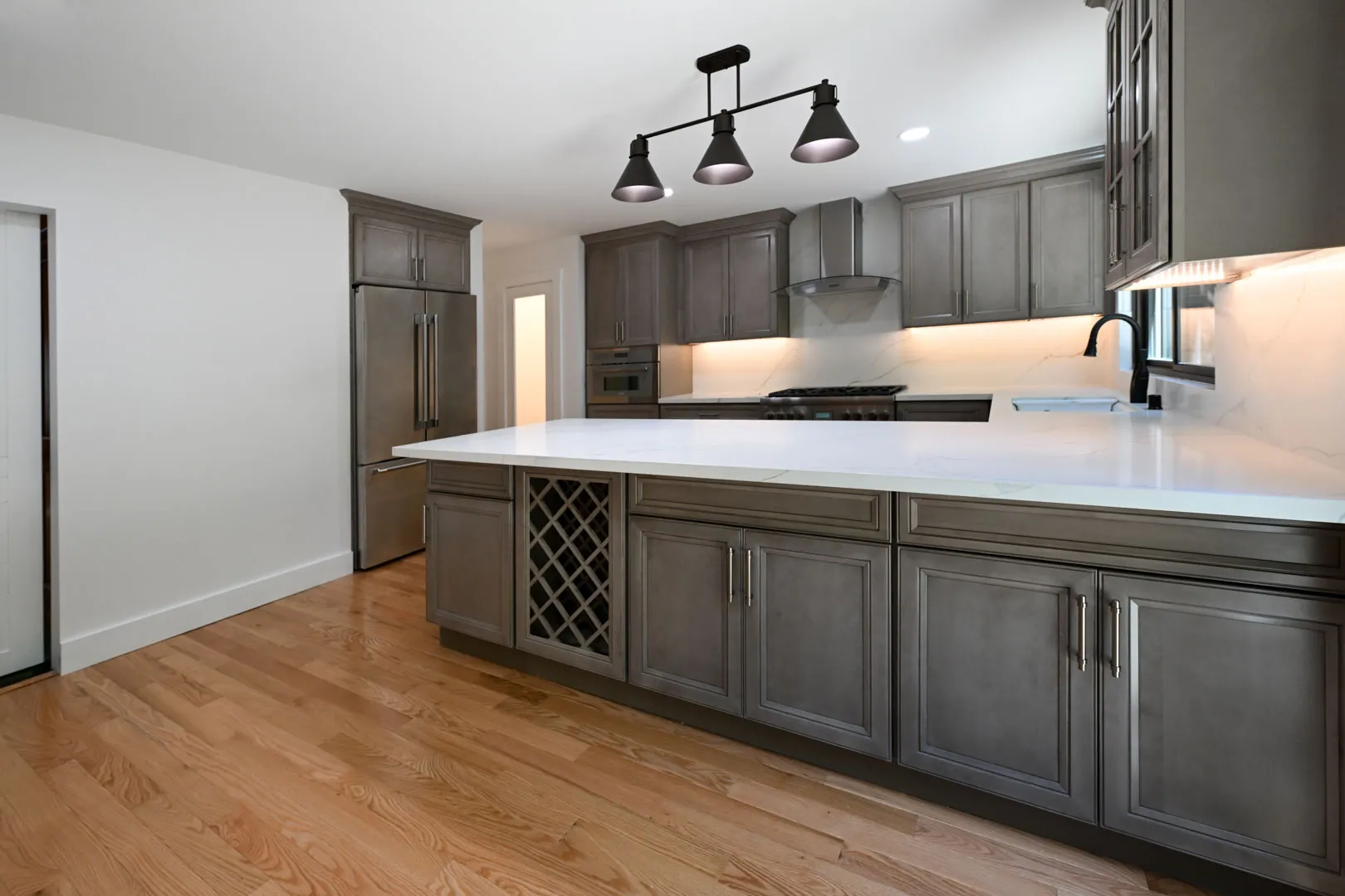 Contemporary kitchen remodel in Sausalito, CA featuring gray shaker cabinets, white quartz countertops, stainless steel appliances, and built-in wine storage.
